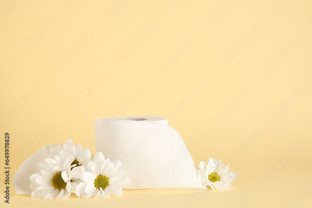 Composition with roll of toilet paper and chamomile flowers on color background