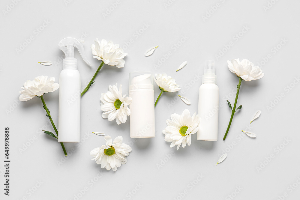 Composition with cosmetic products and chamomile flowers on grey background