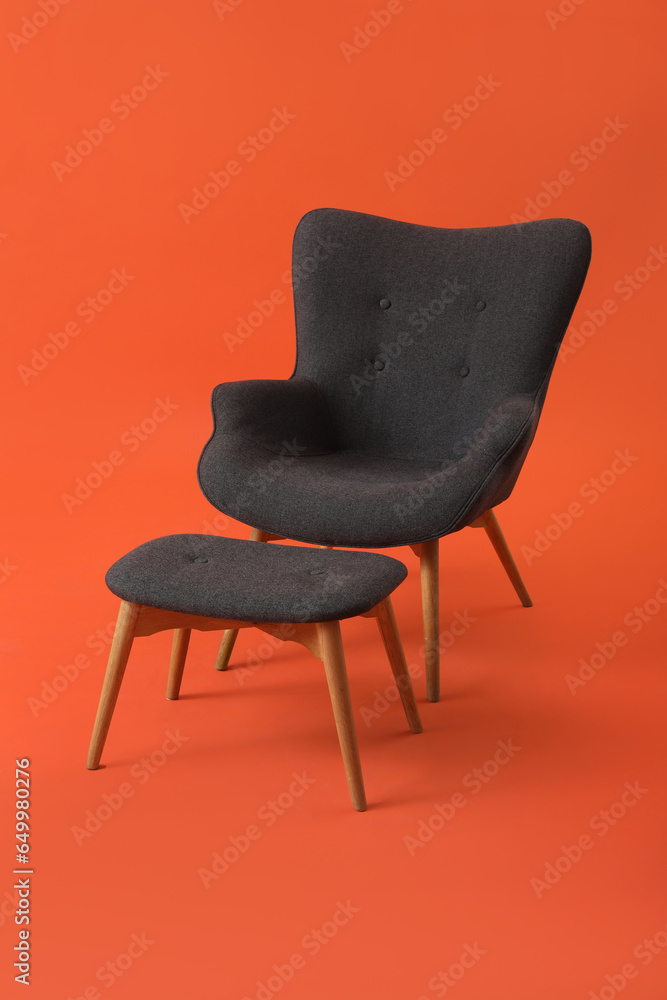 Black armchair with footrest on red background