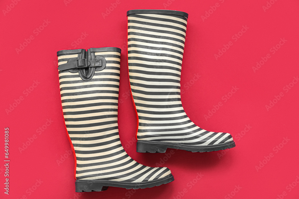 Stylish gumboots on red background