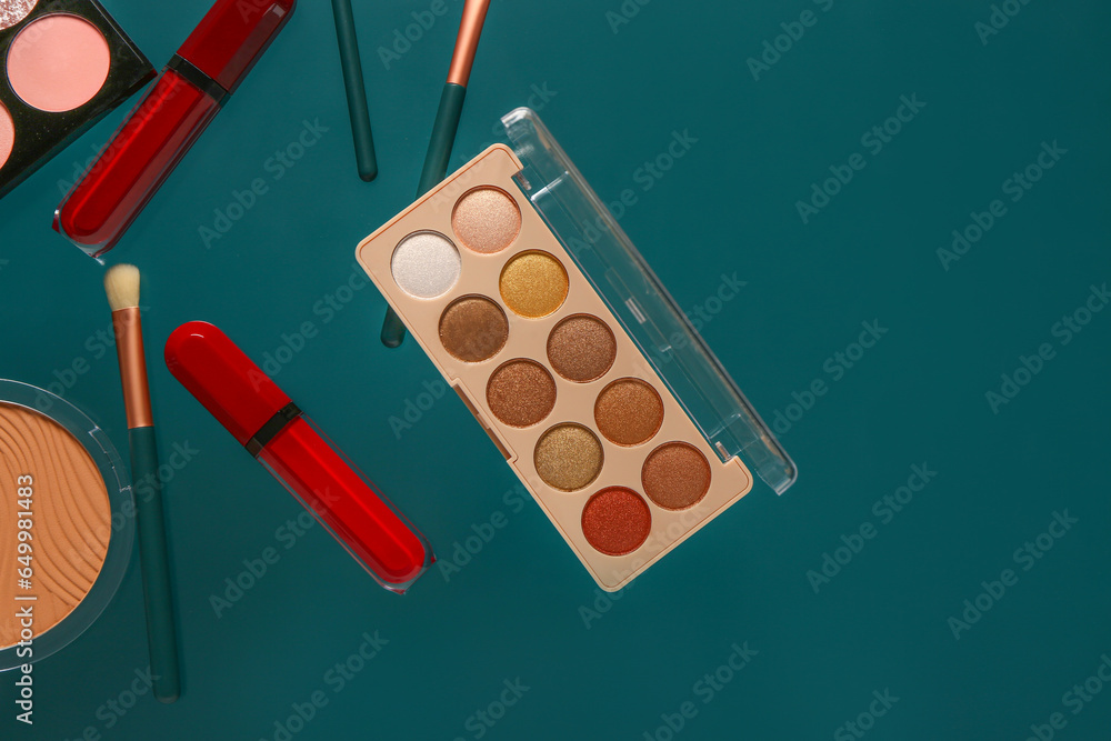 Beautiful palettes of eyeshadows and different decorative cosmetics on green background