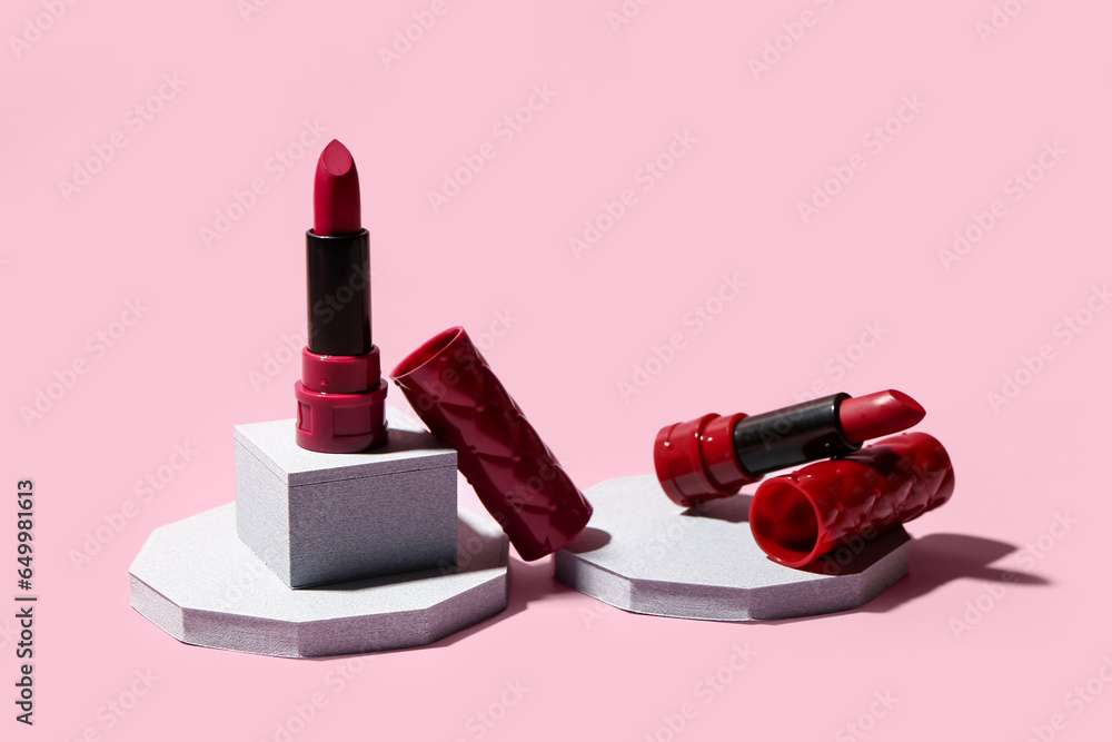 Stands with different bright lipsticks on pink background