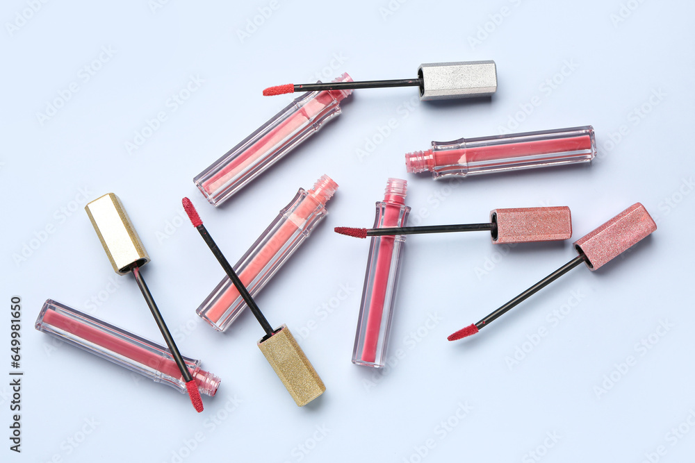 Different stylish pink lipsticks with brushes on blue background