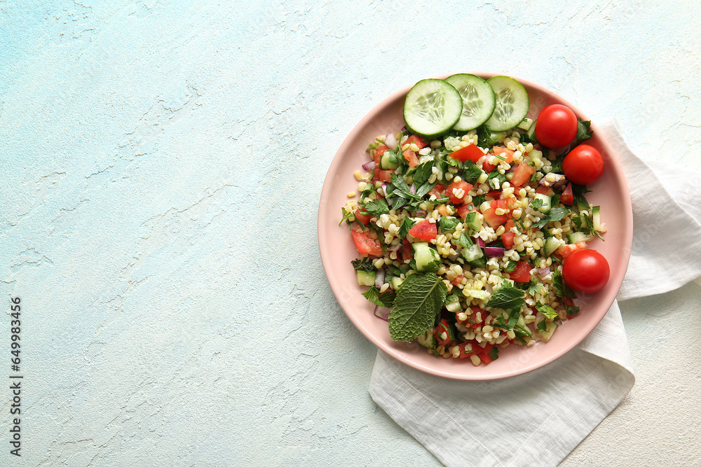 Plate with delicious tabbouleh salad on light background