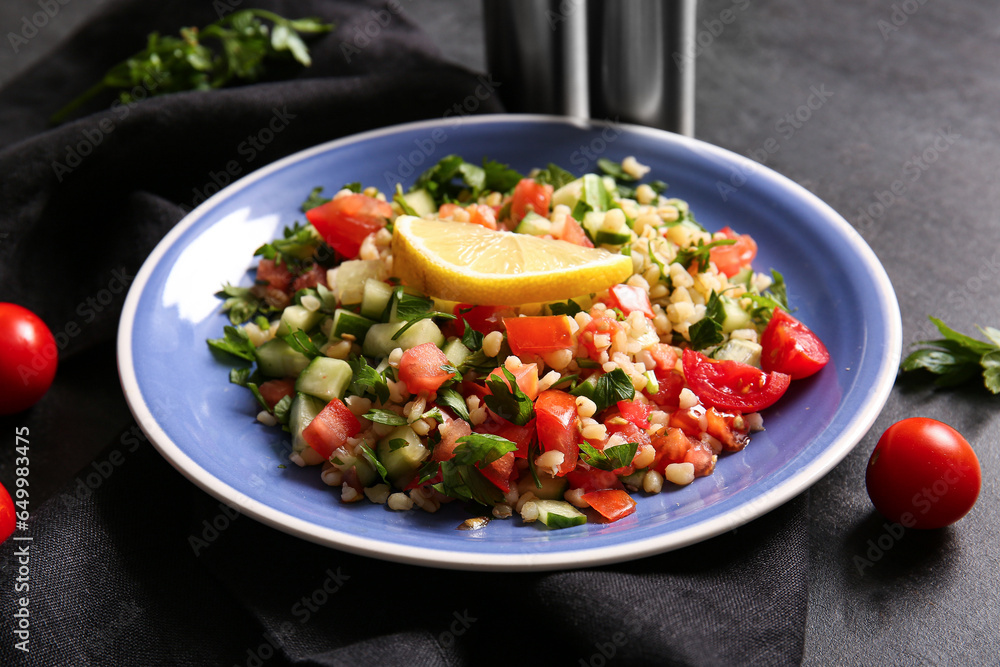 Plate with delicious tabbouleh salad on dark background, closeup