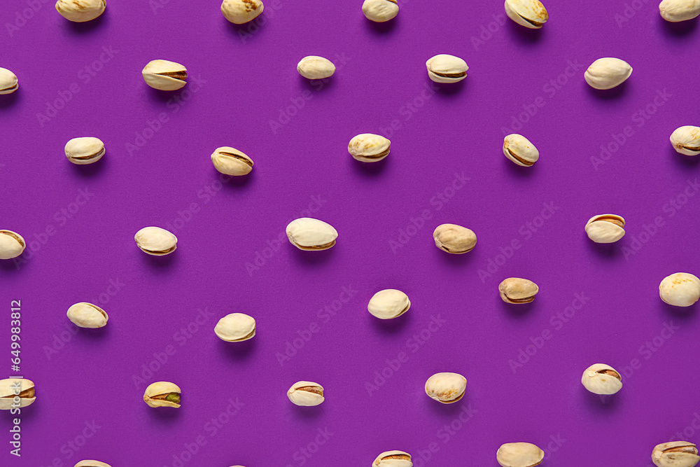 Tasty pistachio nuts on purple background