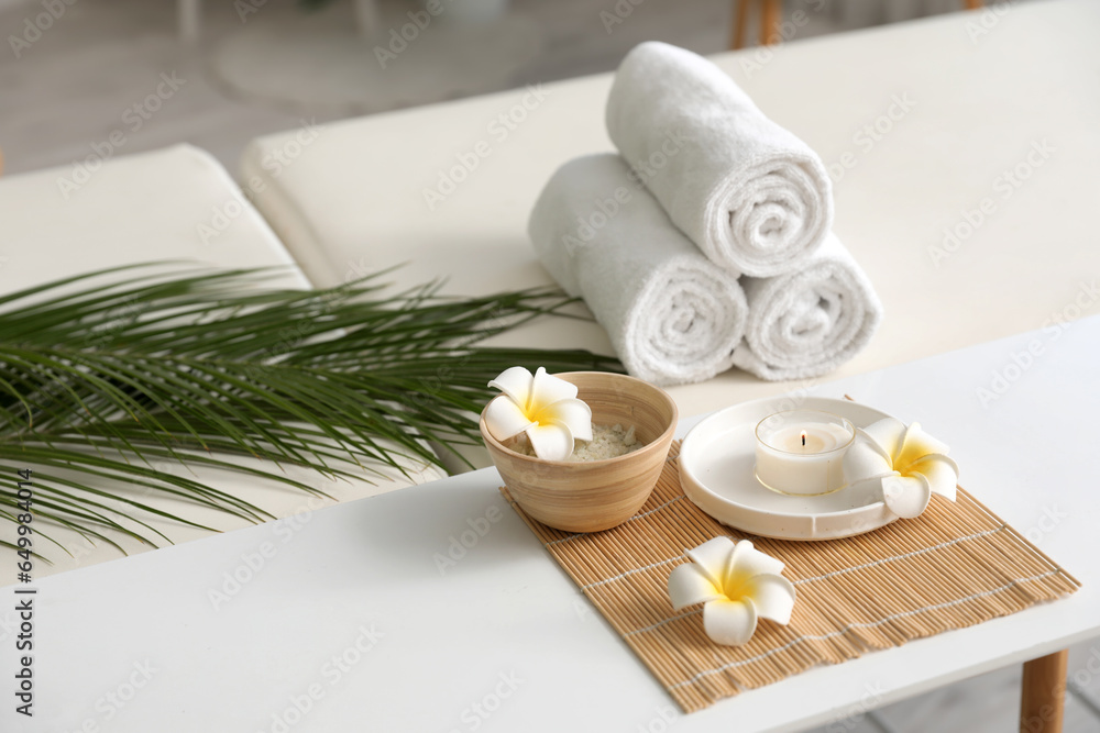 Spa composition with plumeria flowers on table in salon, closeup