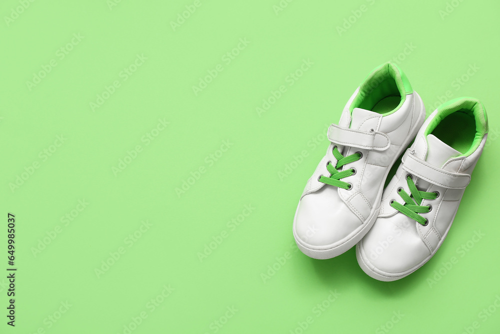 Pair of stylish childs sneakers on green background