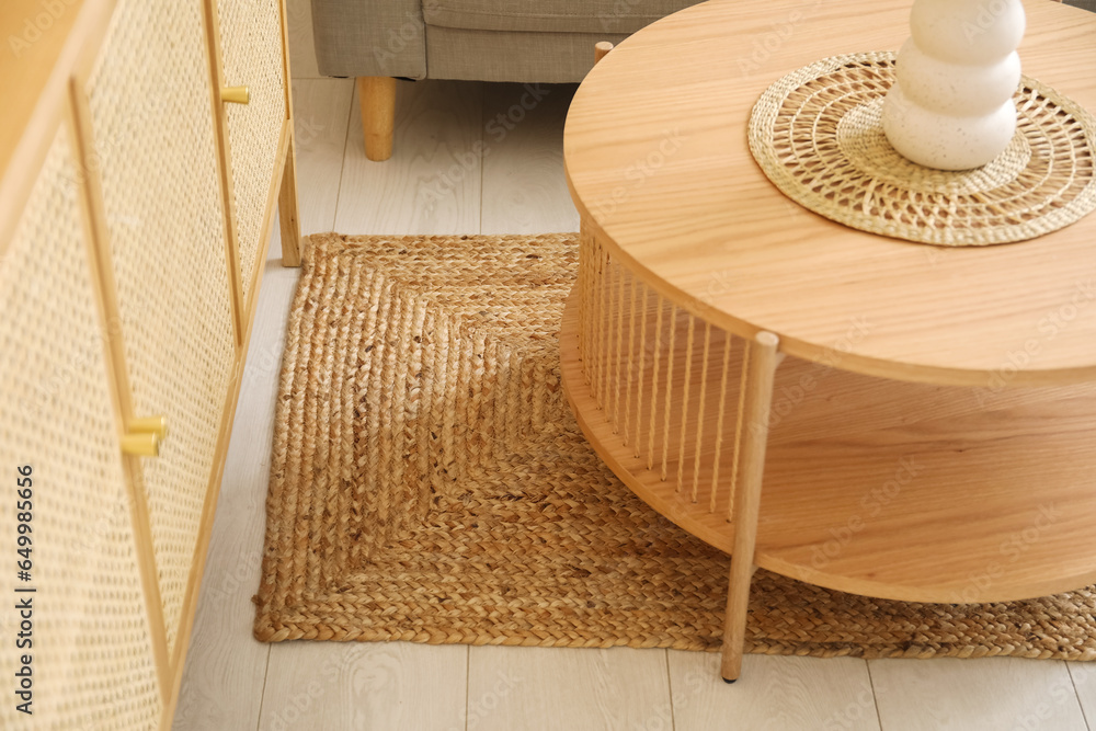 Stylish wicker rug and coffee table with vase in living room