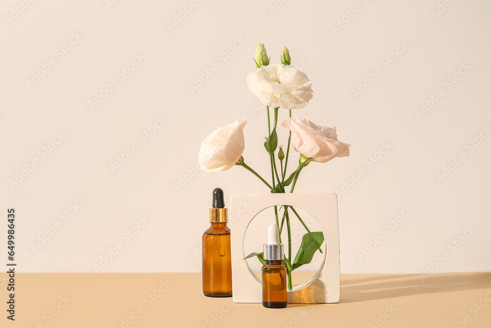 Composition with bottles of essential oil, plaster podium and beautiful eustoma flowers on beige background