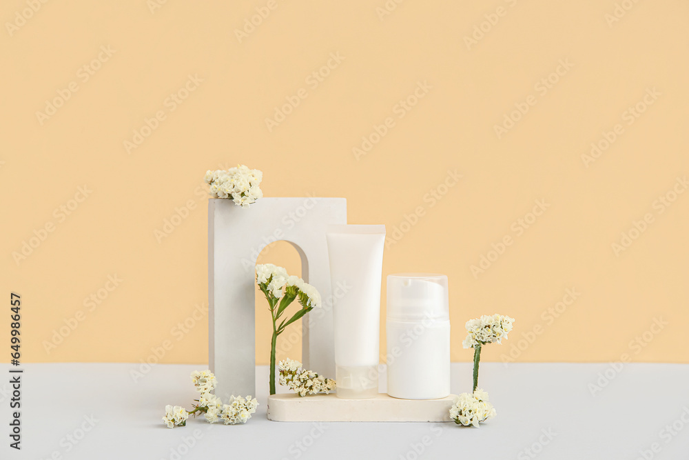 Composition with different cosmetic products, plaster podium and beautiful flowers on beige background