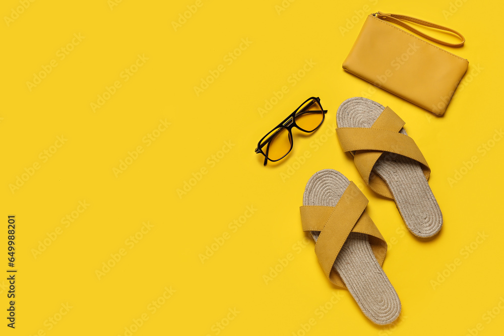 Stylish yellow sandals with purse and sunglasses on color background