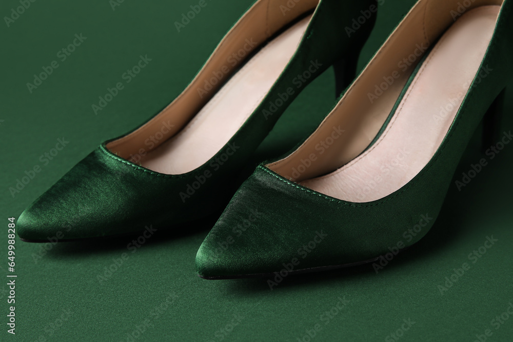 Stylish green high heels on color background