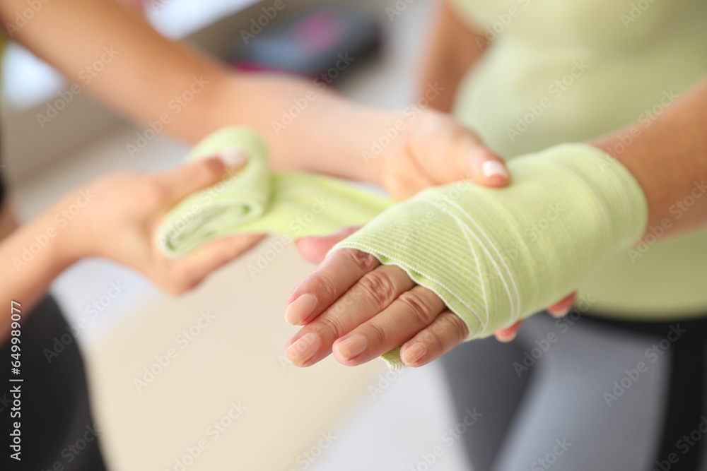 Mature woman with therapist applying wrist wrap in rehabilitation center, closeup