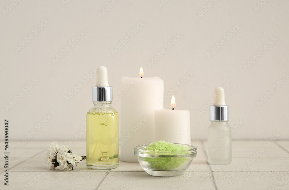 Bottles of essential oil, candles and sea salt on table