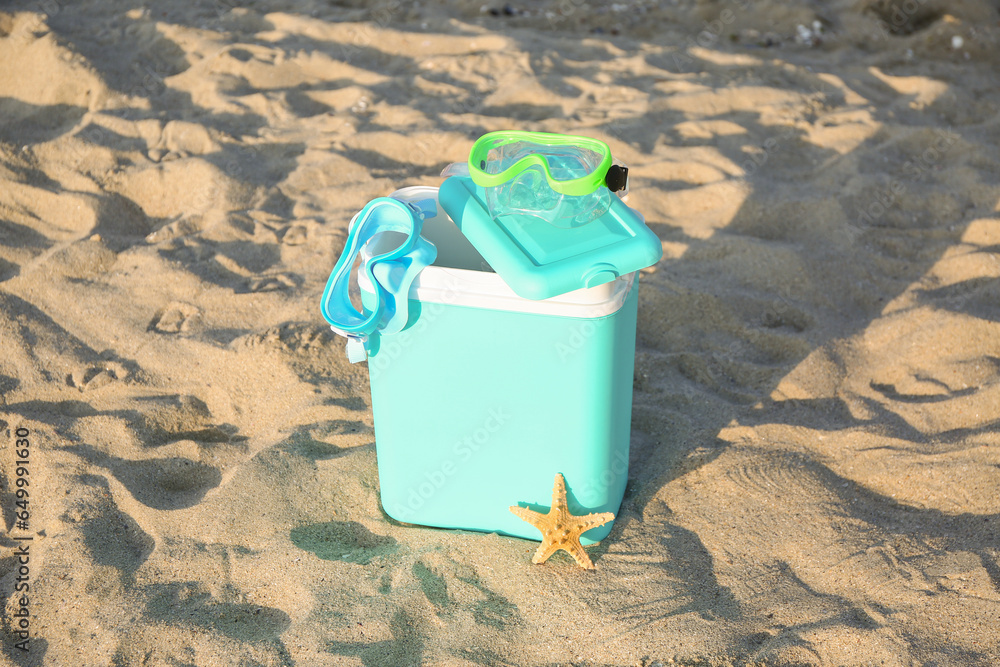 Beach cooler and snorkeling masks on sand