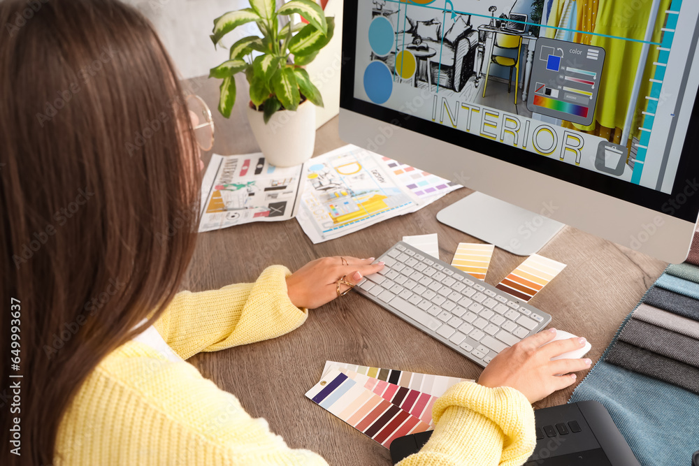 Female interior designer working with computer at table in office