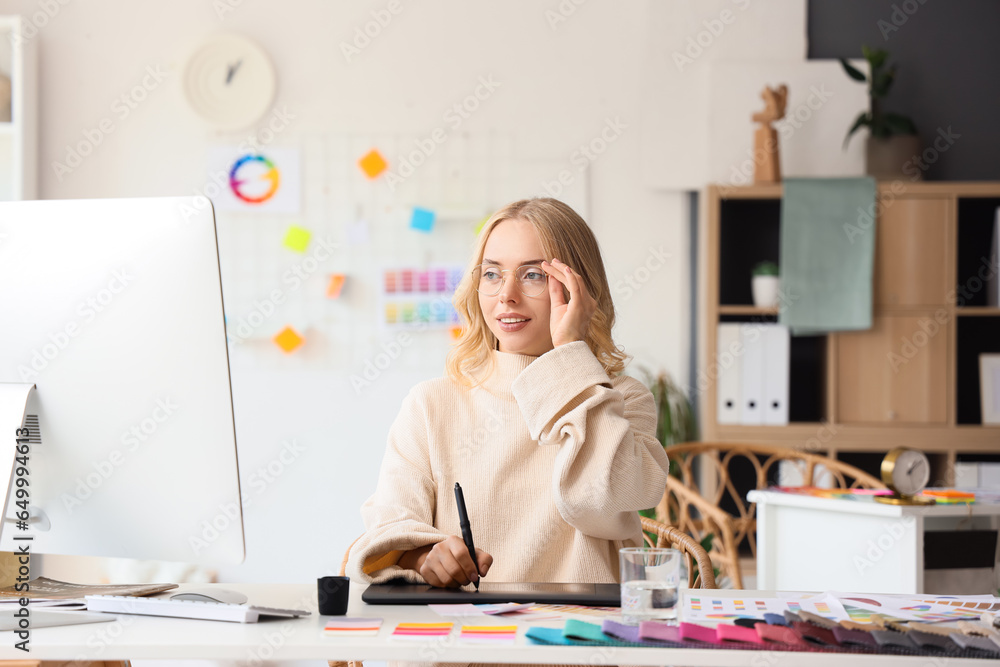 Female interior designer working with graphic tablet at table in office