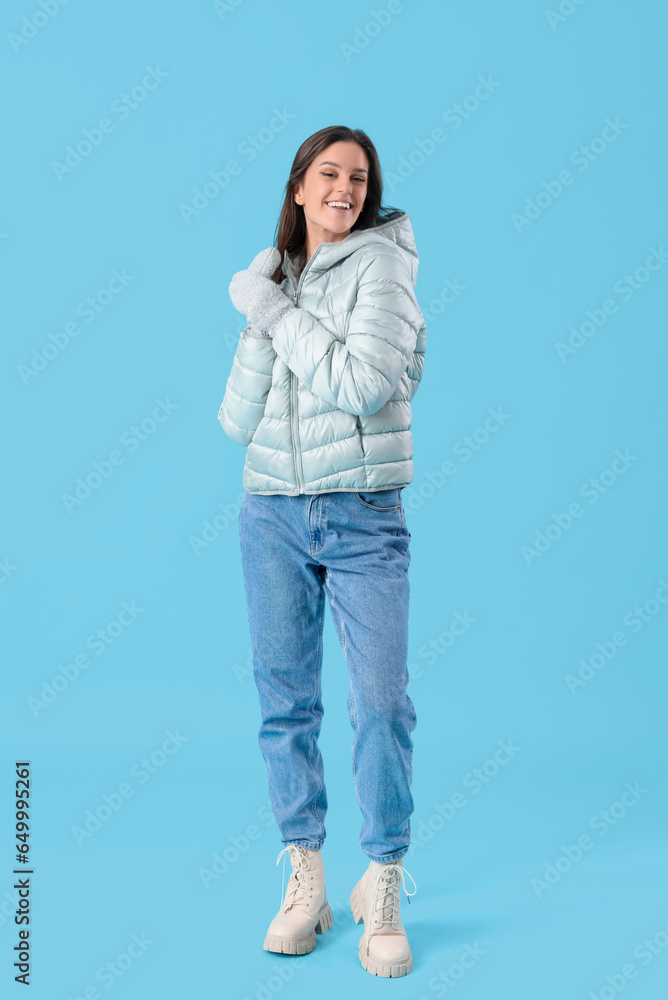 Young woman in winter clothes on blue background