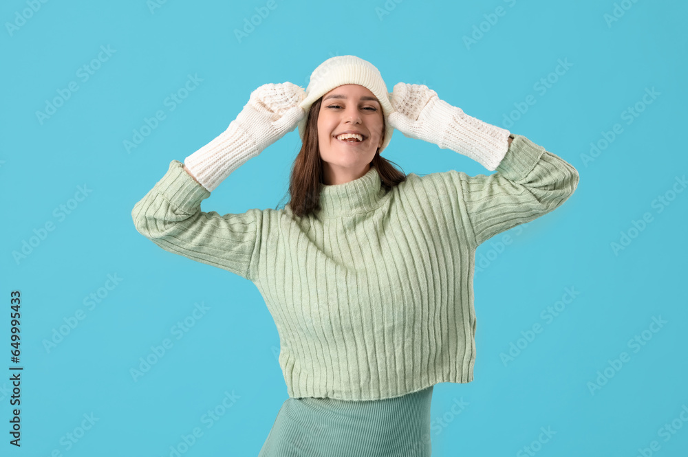 Young woman in winter clothes on blue background