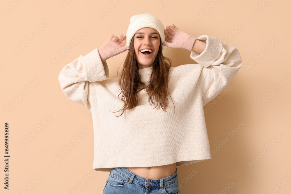 Young woman in winter clothes on beige background