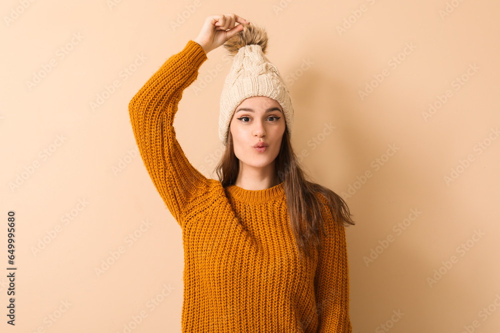 Young woman in winter clothes on beige background