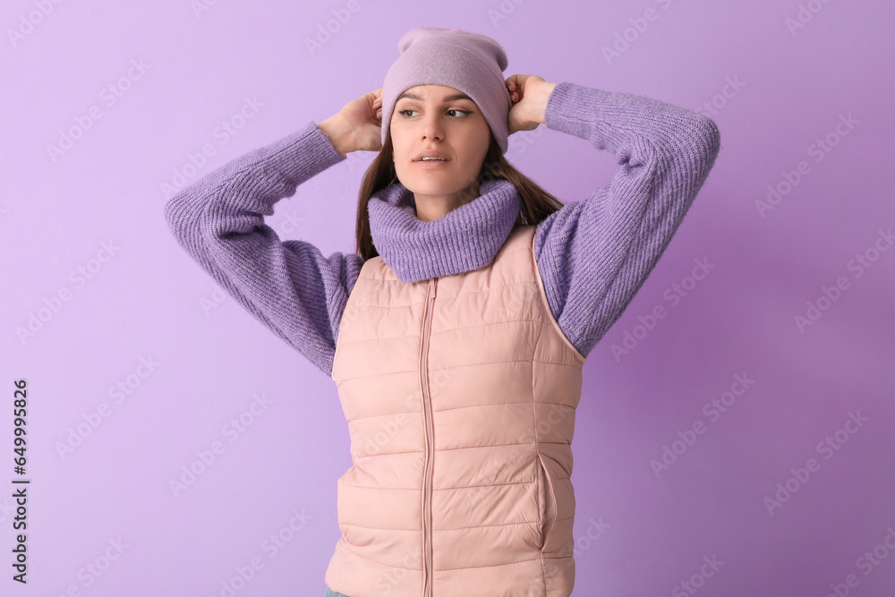 Young woman in winter clothes on lilac background