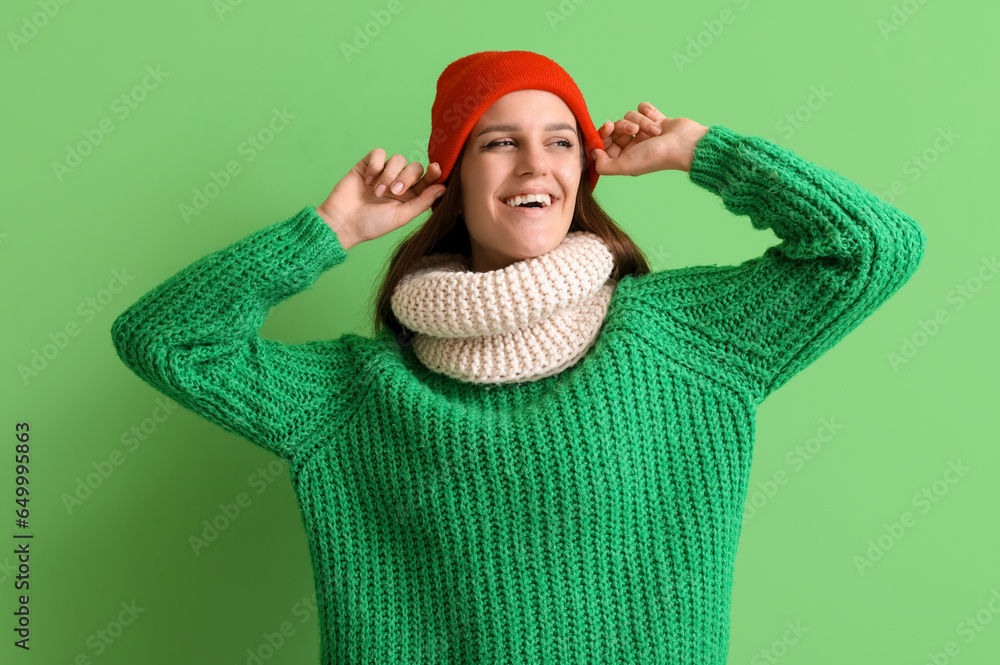 Happy young woman in winter clothes on green background