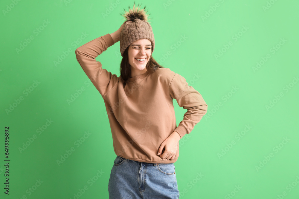 Happy young woman in winter clothes on green background