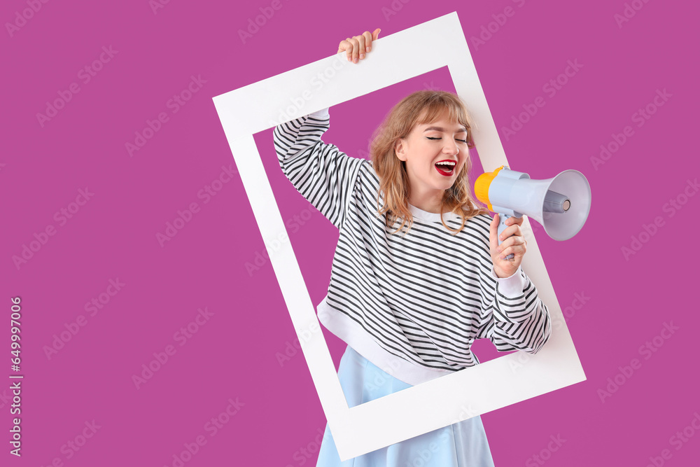 Young woman with frame shouting into megaphone on purple background