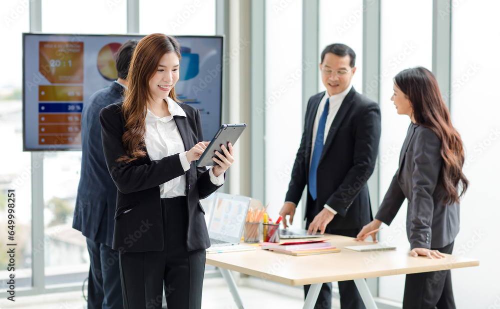 Portrait shot of Asian professional successful female businesswoman manager entrepreneur in formal suit standing smiling looking at camera holding touchscreen tablet computer in company meeting room