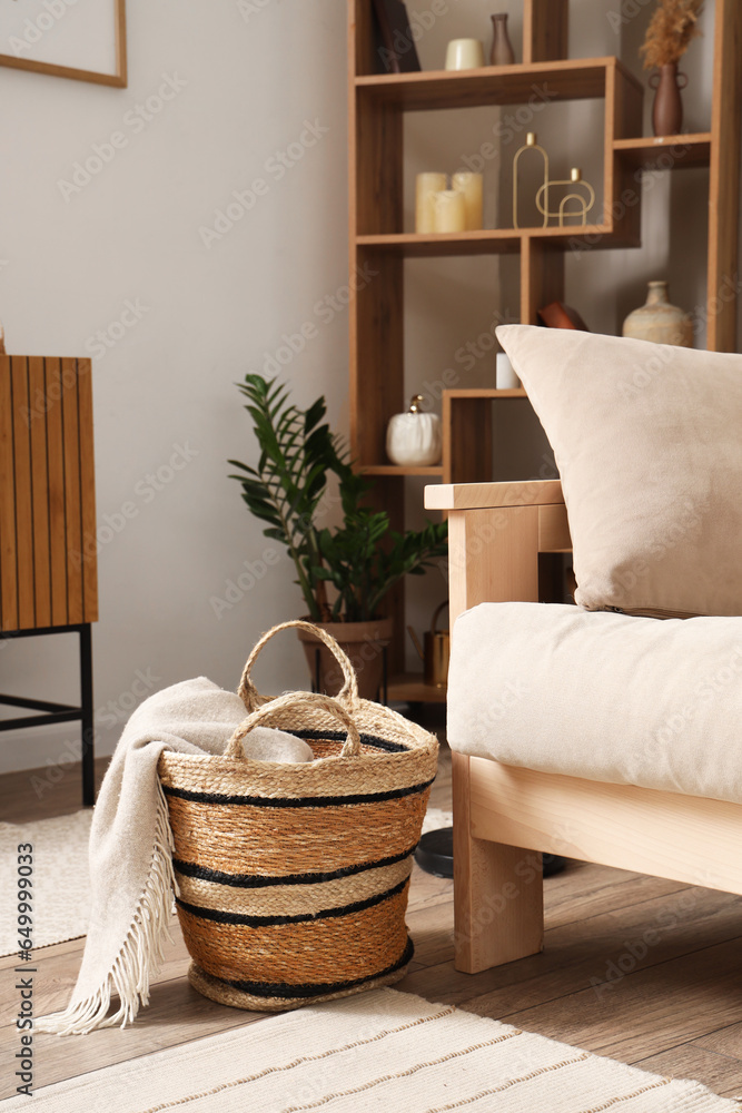 Basket with plaid near sofa in living room