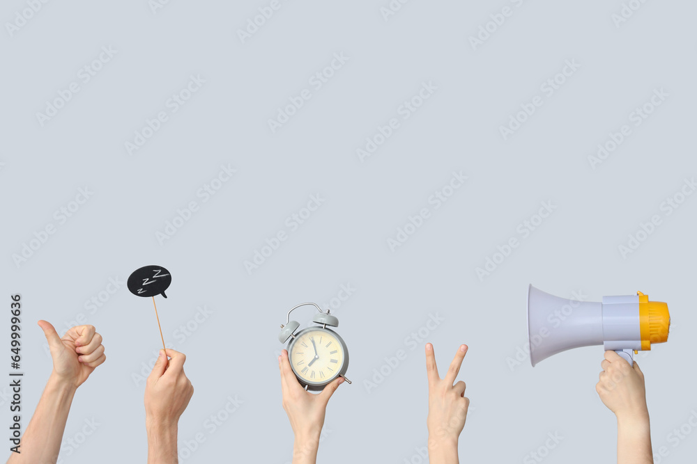 Hands holding alarm clock, megaphone and speech bubble on grey background