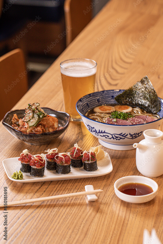 Table with japanese lunch dishes ramen sushi and beer