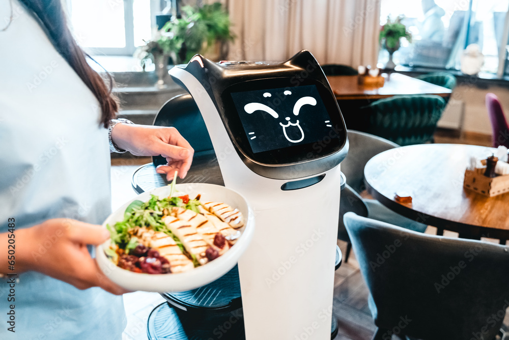 Robot waiter serve food at modern restaurant table.Offering innovation futuristic high-tech automated dining experience.Bringing,delivery automation order to customer.Digital robotic AI smart service