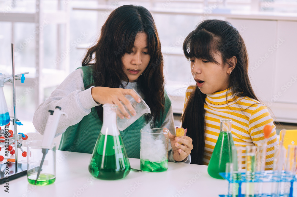 Group of teenage cute little students child learning research and doing a chemical experiment while making analyzing and mixing liquid in test tube at experiment laboratory class at school.Education