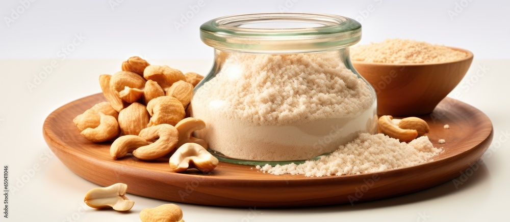 Close up of vegan Parmesan cheese made from raw ground cashew nuts in a jar with cashew nuts on a white background