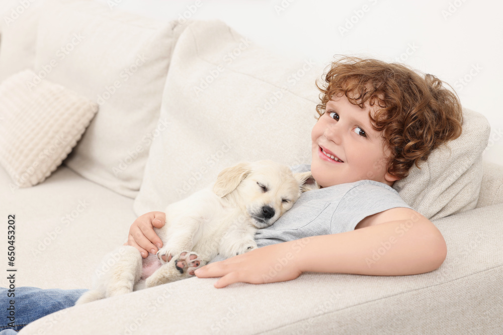 Little boy hugging cute puppy on couch