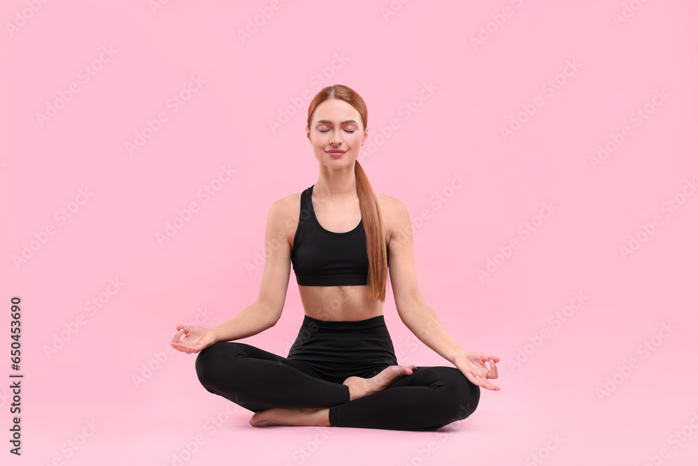 Beautiful young woman practicing yoga on pink background. Lotus pose