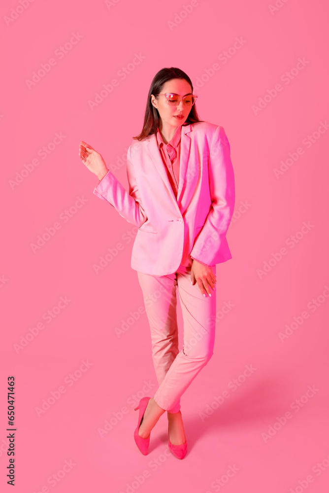 Young woman in stylish suit on pink background