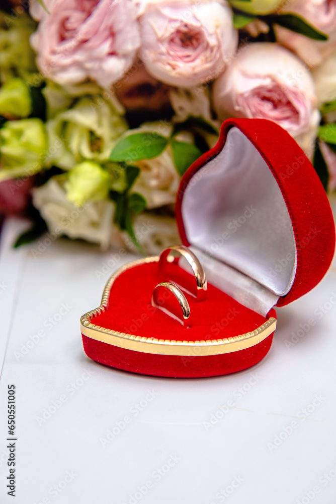 Wedding rings lie on a bouquet of pink roses 