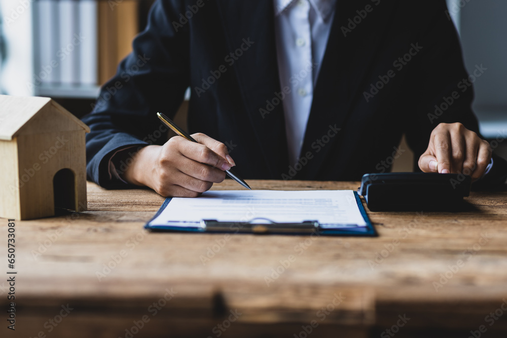 Businesswoman, real estate agent reading contract documents and calculating real estate budget.