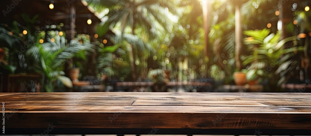 Wooden table in tropical setting with blurred garden cafe lights ideal for showcasing products in business presentations