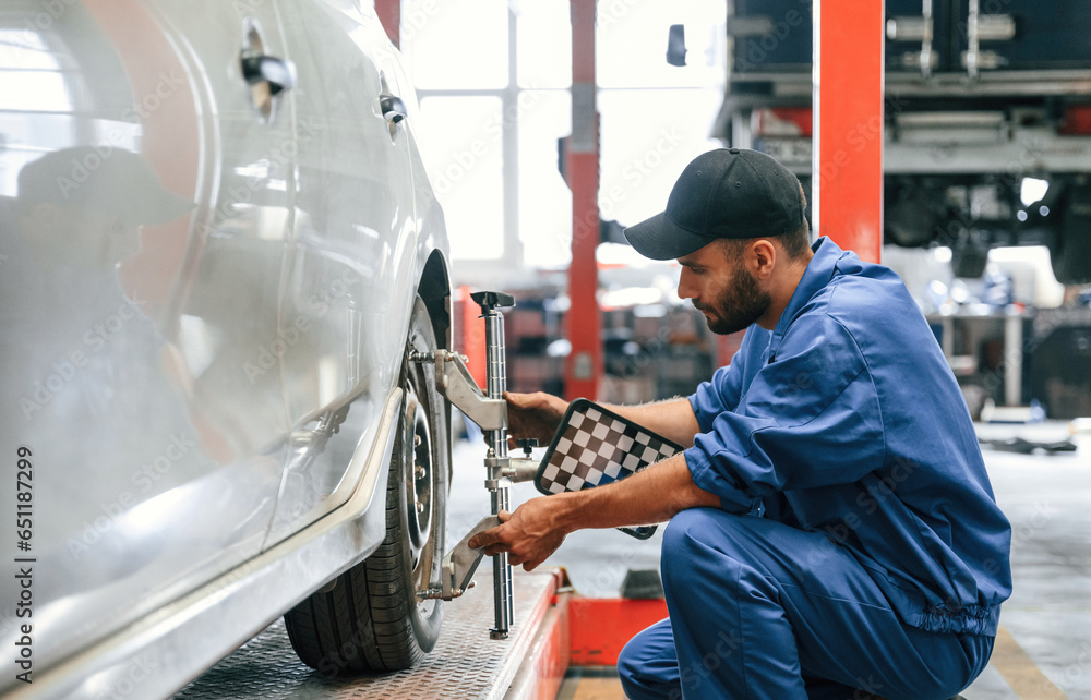 Taking care of wheel disk. Auto mechanic working in garage. Repair service