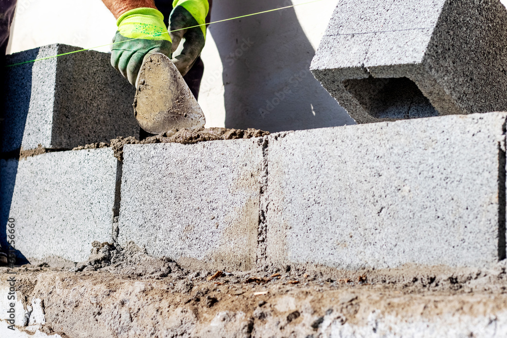 A builder holds a trowel during the construction of a wall made of aerated concrete blocks