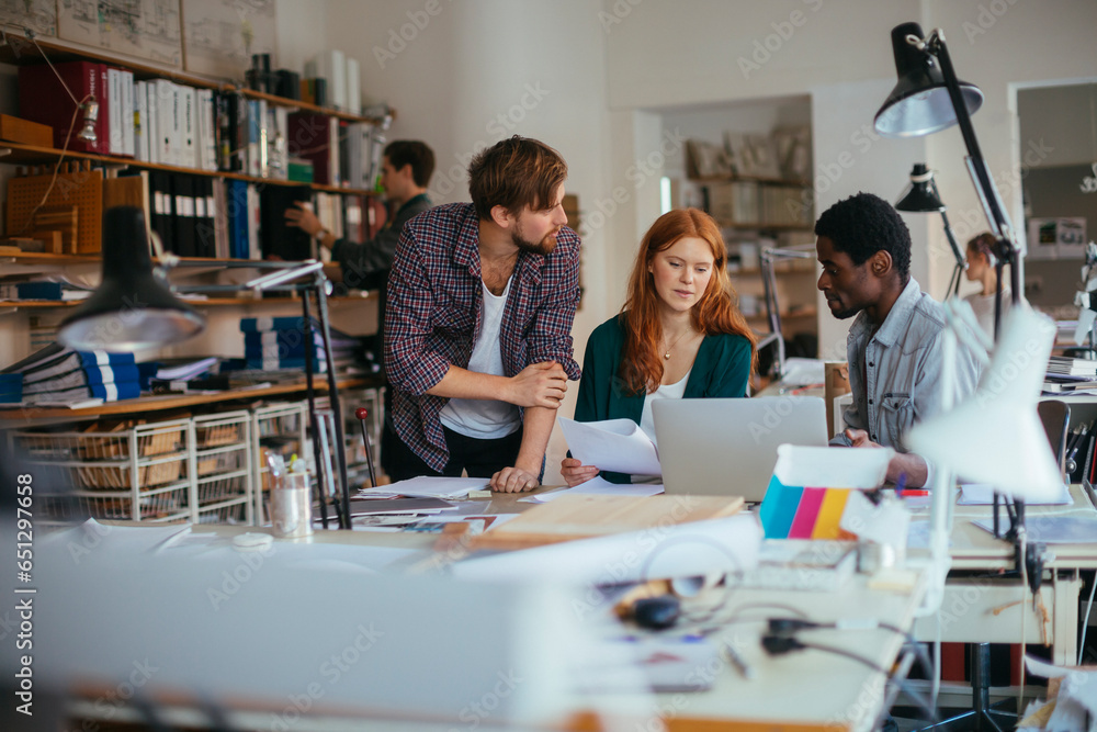 Young and diverse group of architects using a laptop and working together in a startup company office