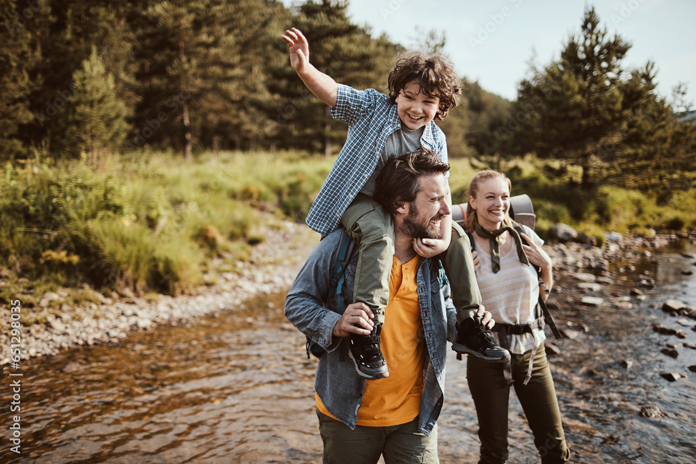 Young family crossing a creek while hiking in the forest and mountains