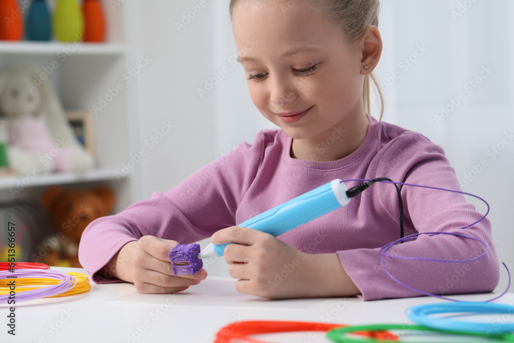 Girl drawing with stylish 3D pen at white table indoors