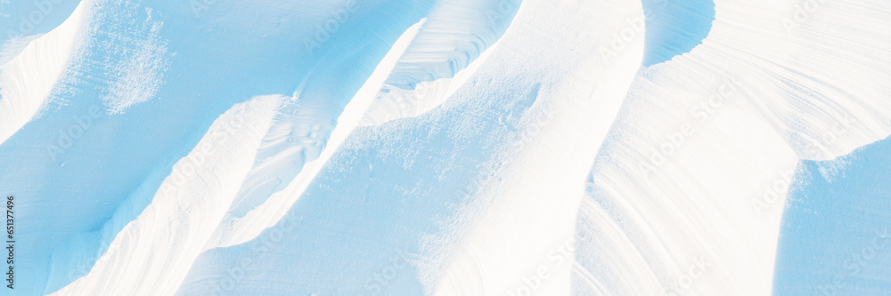 Snow texture. Wind sculpted patterns on snow surface. Wind in the tundra and in the mountains on the surface of the snow sculpts patterns and ridges (sastrugi). Arctic, Polar region. Winter background