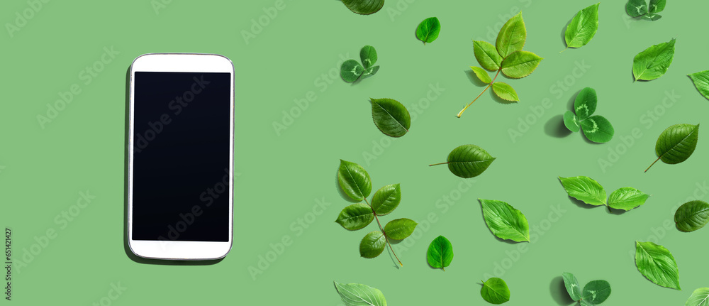 White smartphone with green leaves - flat lay